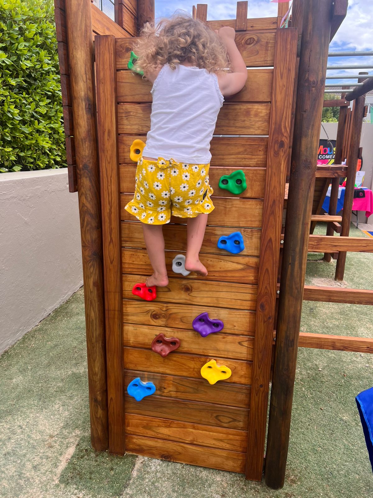 Child climbing the outdoor wooden wall