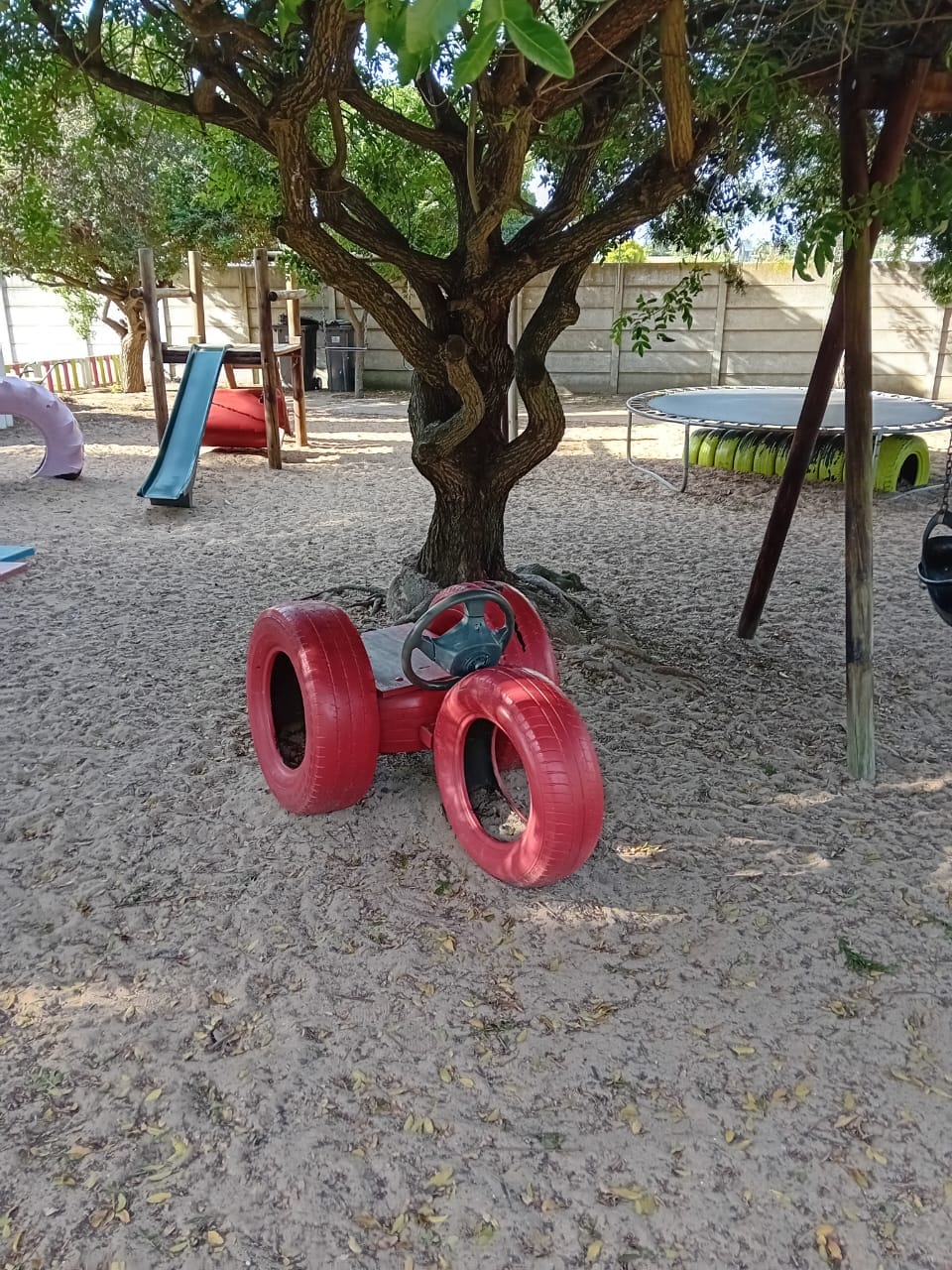 Children playing under the tree with the orange tyre car