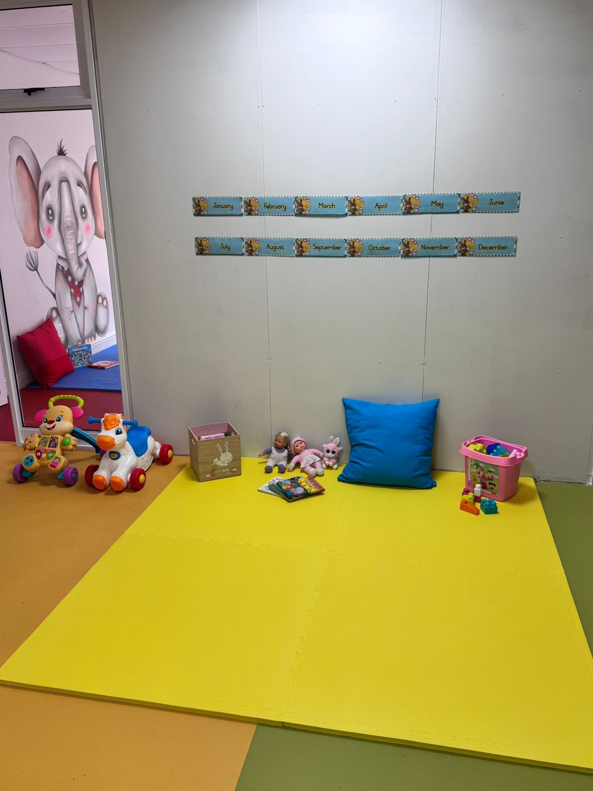 Yellow play mat room with toys and friendly elephant mural